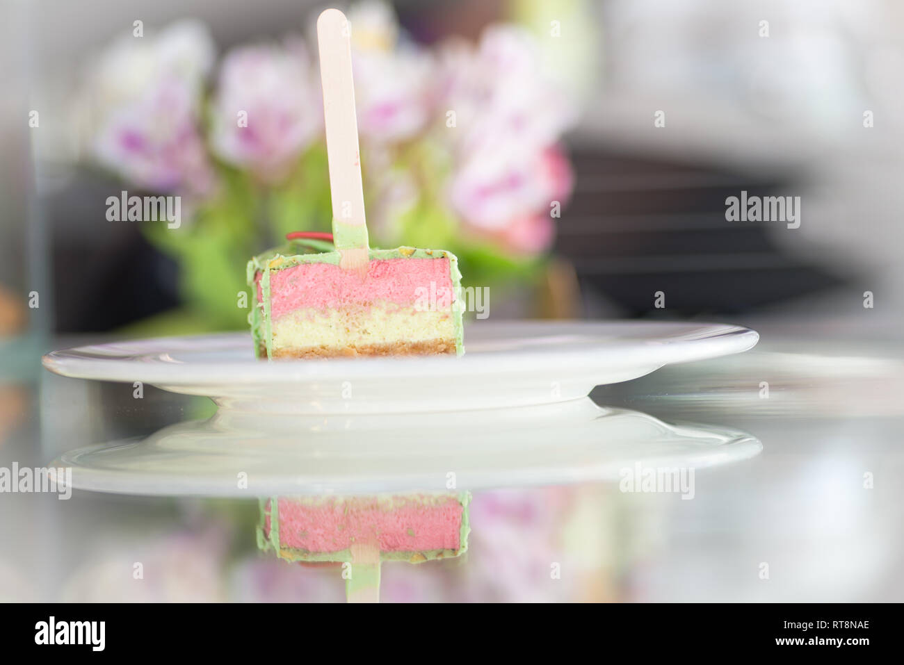 Tre strati torta, con smalto verde e alcuni fiori a sfondo Foto Stock