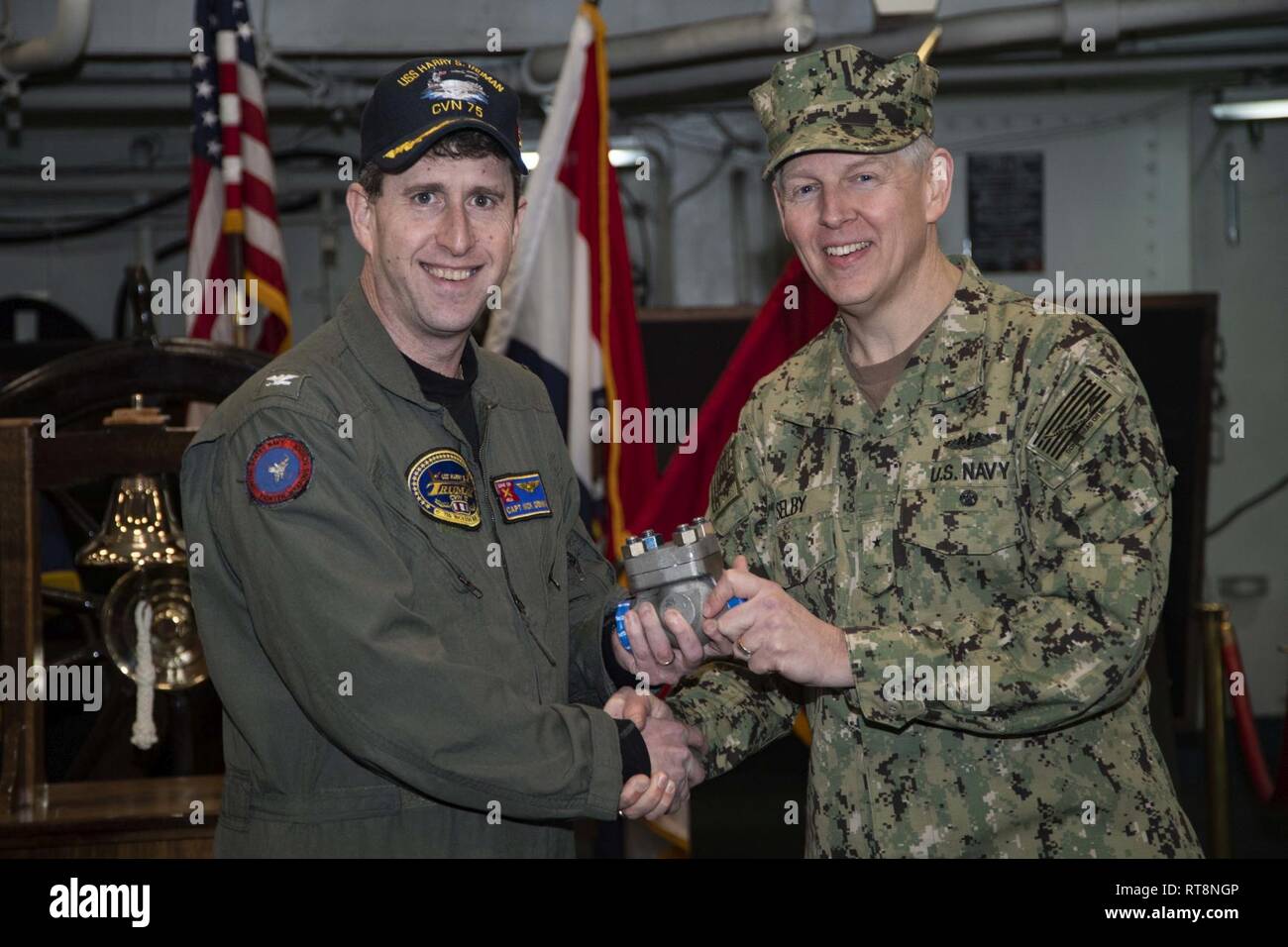 NORFOLK, Virginia (GEN. 29, 2019) Naval Sea Systems Command Chief Engineer e vice comandante per nave Progettazione, integrazione e ingegneria navale, posteriore Adm. Lorin Selby, destra presenta USS Harry Truman (CVN 75) comandante, cap. Nicholas Dienna, con le prime 3-D stampato parte in metallo per l'installazione e l'uso su un U.S. Navy portaerei. Il gruppo di tubazioni, fabbricato da Huntington Ingalls Industries, verrà installato e valutati per un periodo di un anno. Foto Stock