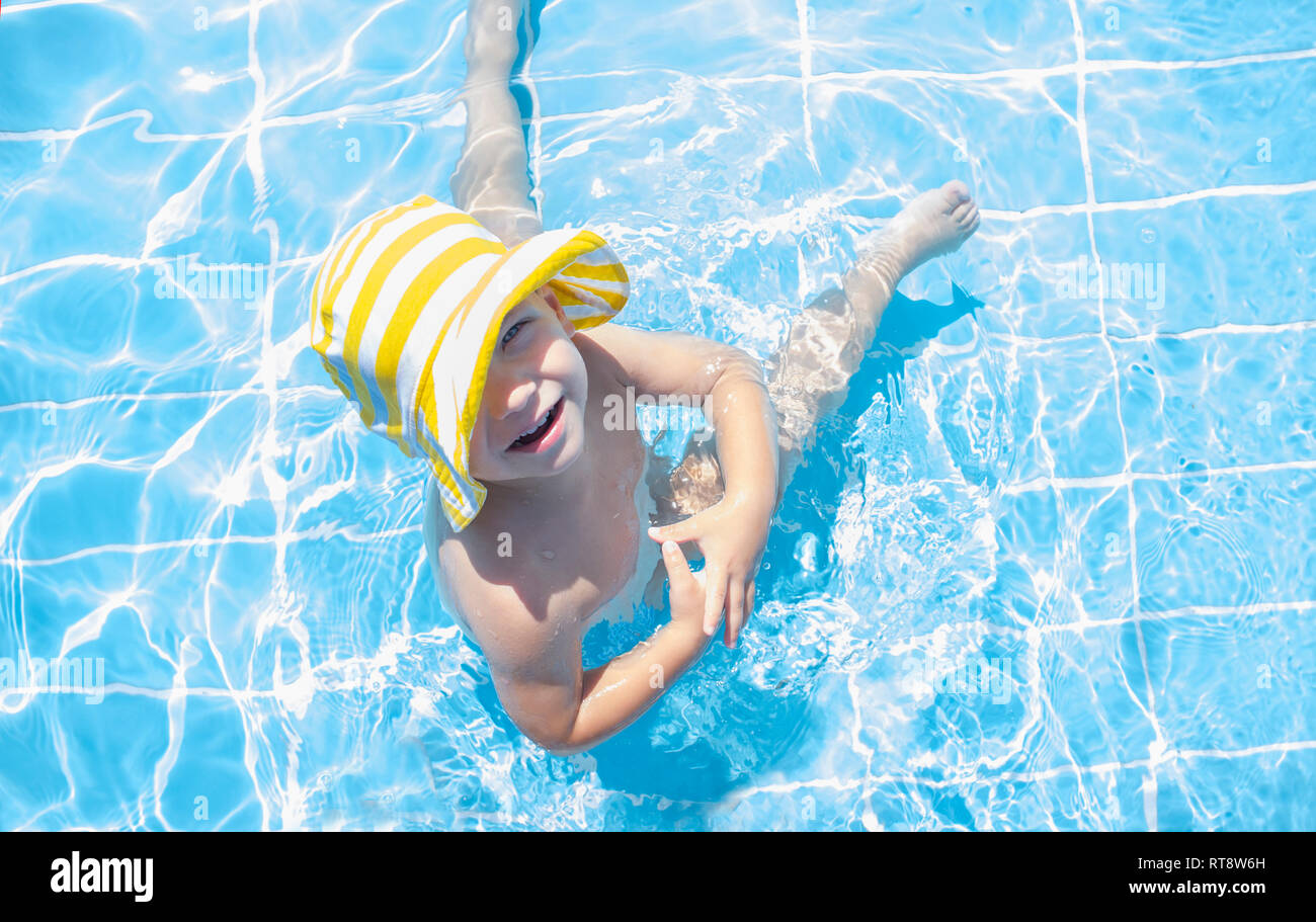 3 anni toddler boy godendo piscina all'area poco profonda. Egli indossa giallo spogliato hat Foto Stock