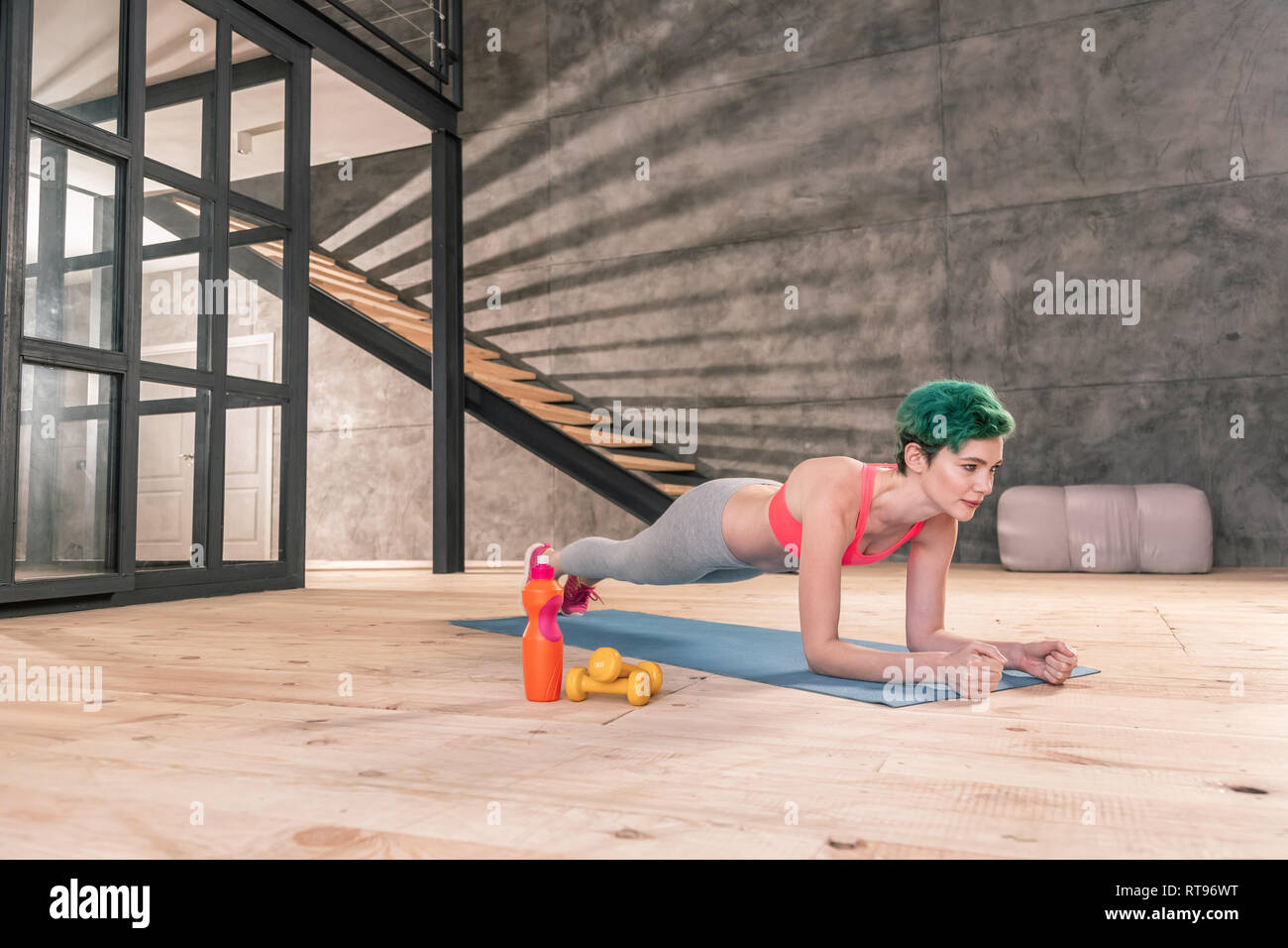 Con capelli verdi sportive facendo mattina plank dopo allenamento Foto Stock