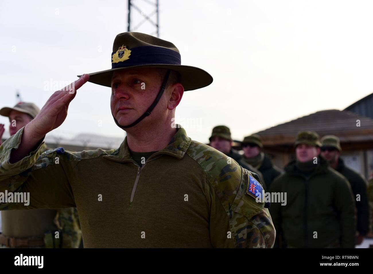 Sito ufficiale della Royal Navy Commander Sands Skinner, TAAC-aria direttore di manutenzione, conduce una formazione di salutare la bandiera australiana come si è issato in avanti su una base operativa Oqab, Kabul, Afghanistan, a gennaio 26, 2019. È stato in questo giorno nel 1788 quando capitano Arthur Phillip comandato la prima flotta a Sydney Cove, Australia. Foto Stock