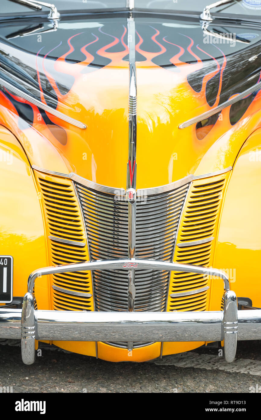 Hook, Regno Unito - 1 Gennaio 2019: Close-up di una griglia cromata e vivido giallo tramonto e verniciatura di fiamma su un custom Ford V8 hotrod in Hook, Regno Unito Foto Stock
