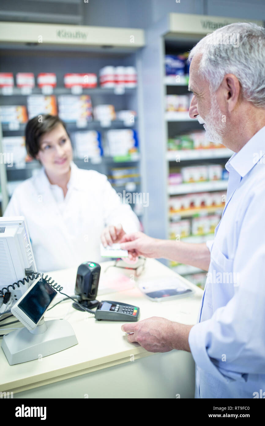 Il cliente di pagare senza contanti in farmacia Foto Stock
