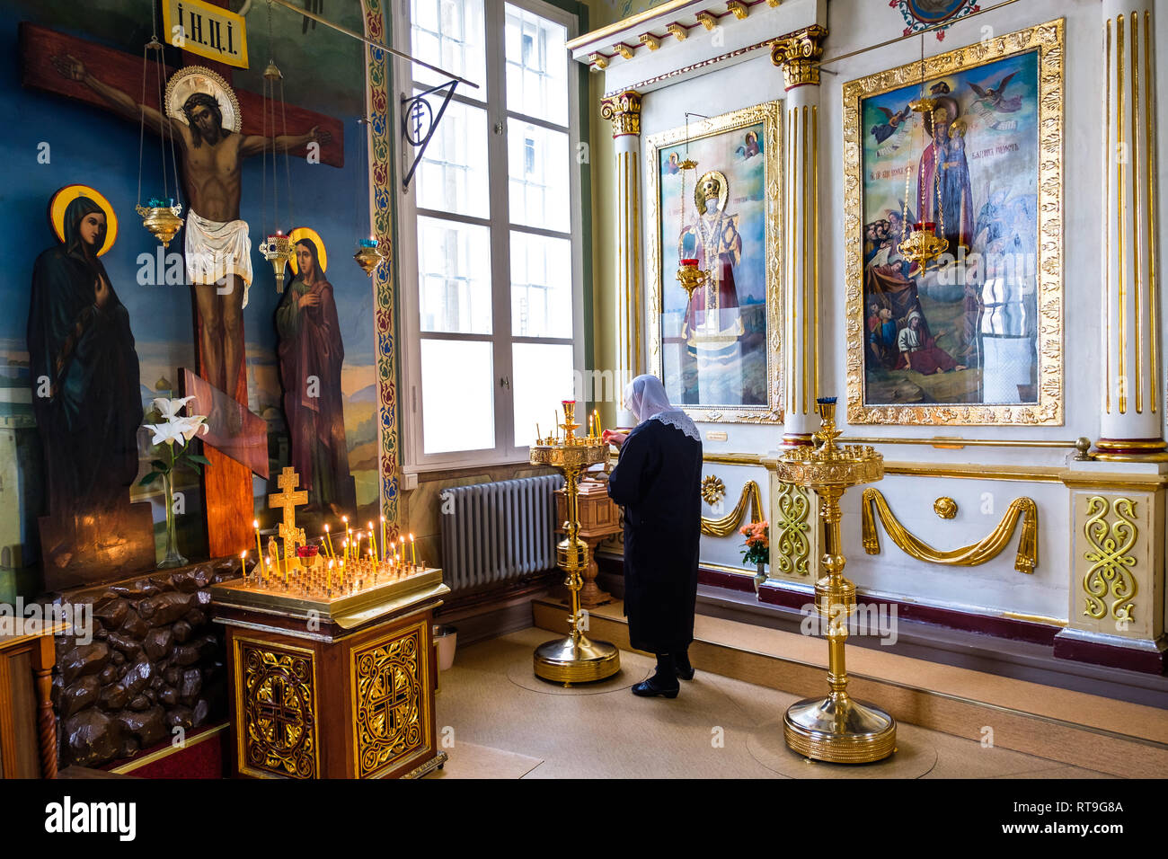 Lettonia : Riga. San Alexander Nevsky chiesa neo-classico, in Brivibas street, con una donna che indossa un fichu sul suo capo accendere una candela. Half o Foto Stock