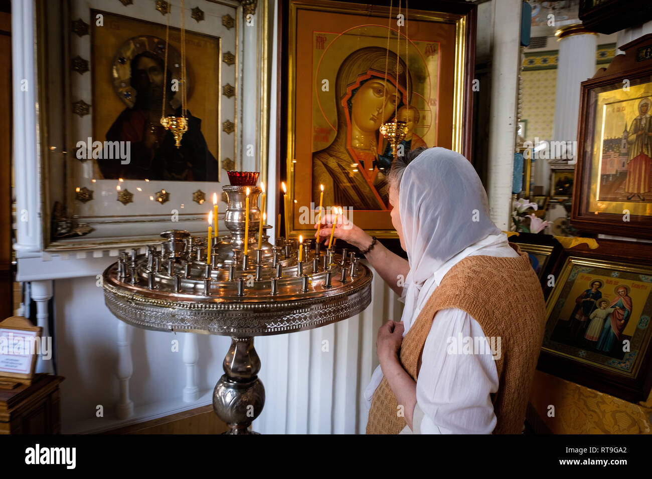 Lettonia : Riga. Riga. All'interno di stile neo-classico St. Alexander Nevsky Chiesa, Brivibas street, una donna che indossa un fichu sulla sua testa una illuminazione può Foto Stock