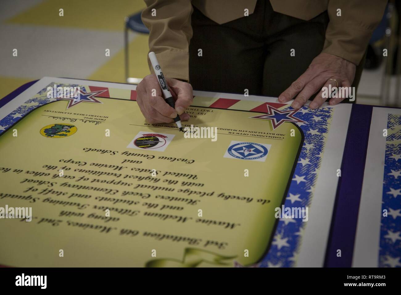 Stati Uniti Marine Corps Sgt. Il Mag. Jennifer Armentrout, squadrone sergente maggiore, Marine medie Tiltrotor Training Squadron 204 (VMMT-204), Marine Aircraft Group 26, 2 aeromobili Marina Wing, segni un annuncio di adozione del partenariato durante il 3 ° Battaglione, 6° Reggimento Marine, seconda divisione Marine e VMMT-204, adottare-a-scuola cerimonia al Hunters Creek Scuola Elementare di Jacksonville, N.C., 1 febbraio 2019. I partner del programma Marine Corps unità con le scuole locali per costruire relazioni nella comunità attraverso il volontariato. Foto Stock