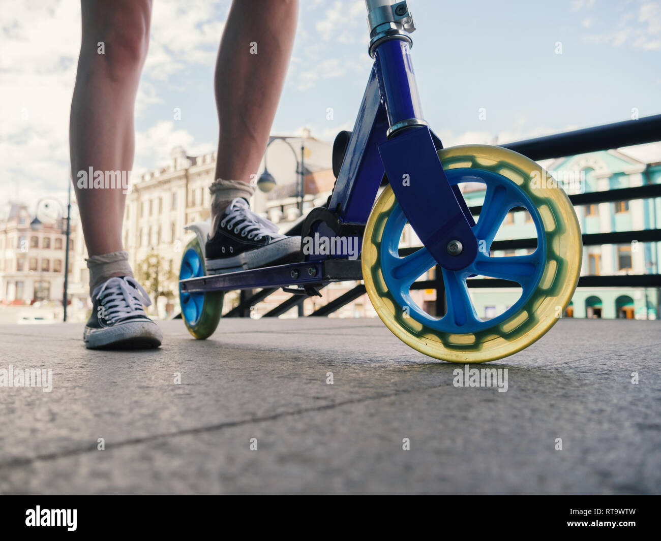 Le gambe della giovane donna su kick scooter a street. Foto Stock