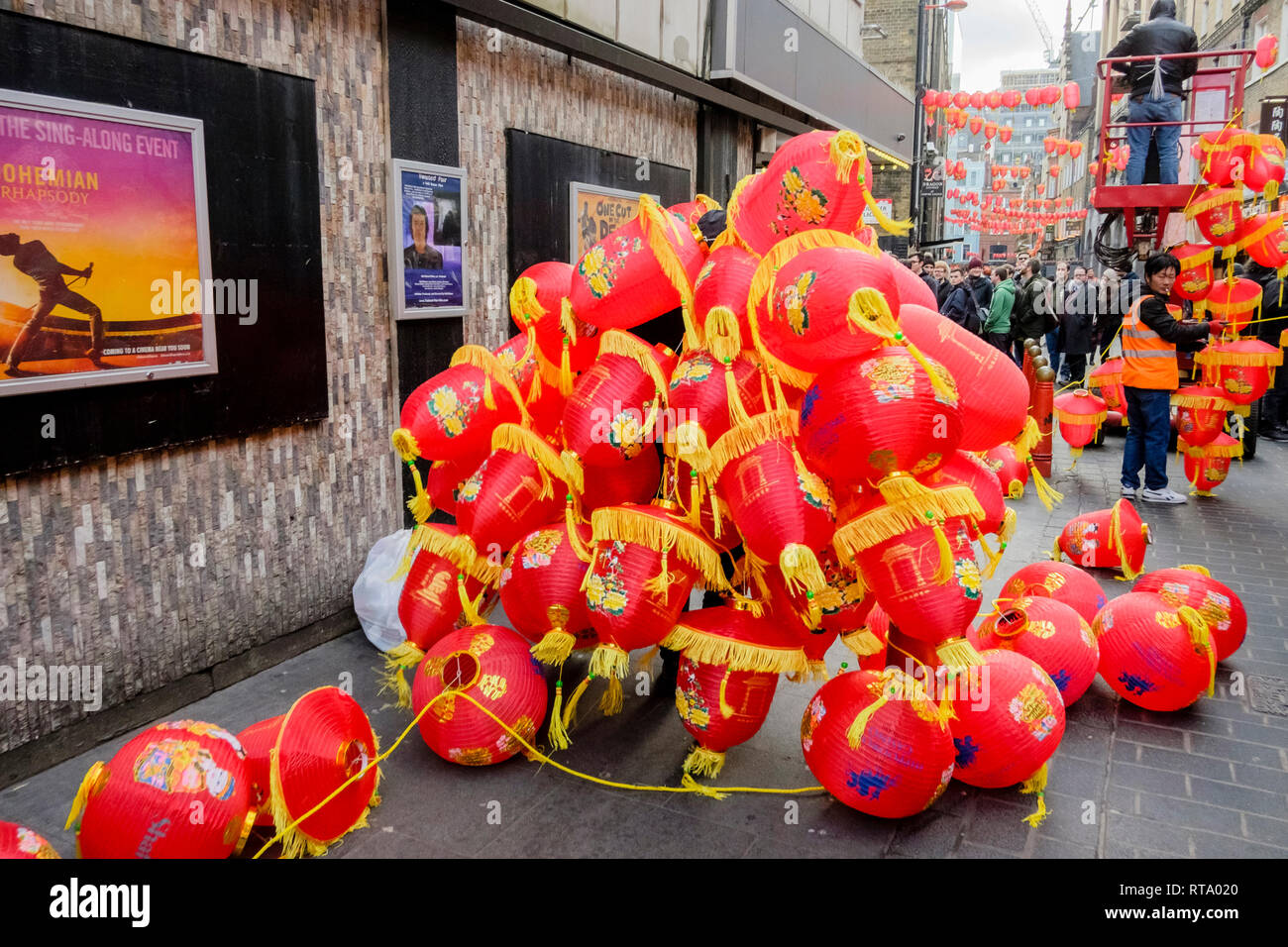 Uomo che porta le lanterne cinesi durante i preparativi per il Capodanno cinese, Lisle Street, Londra, Regno Unito Foto Stock