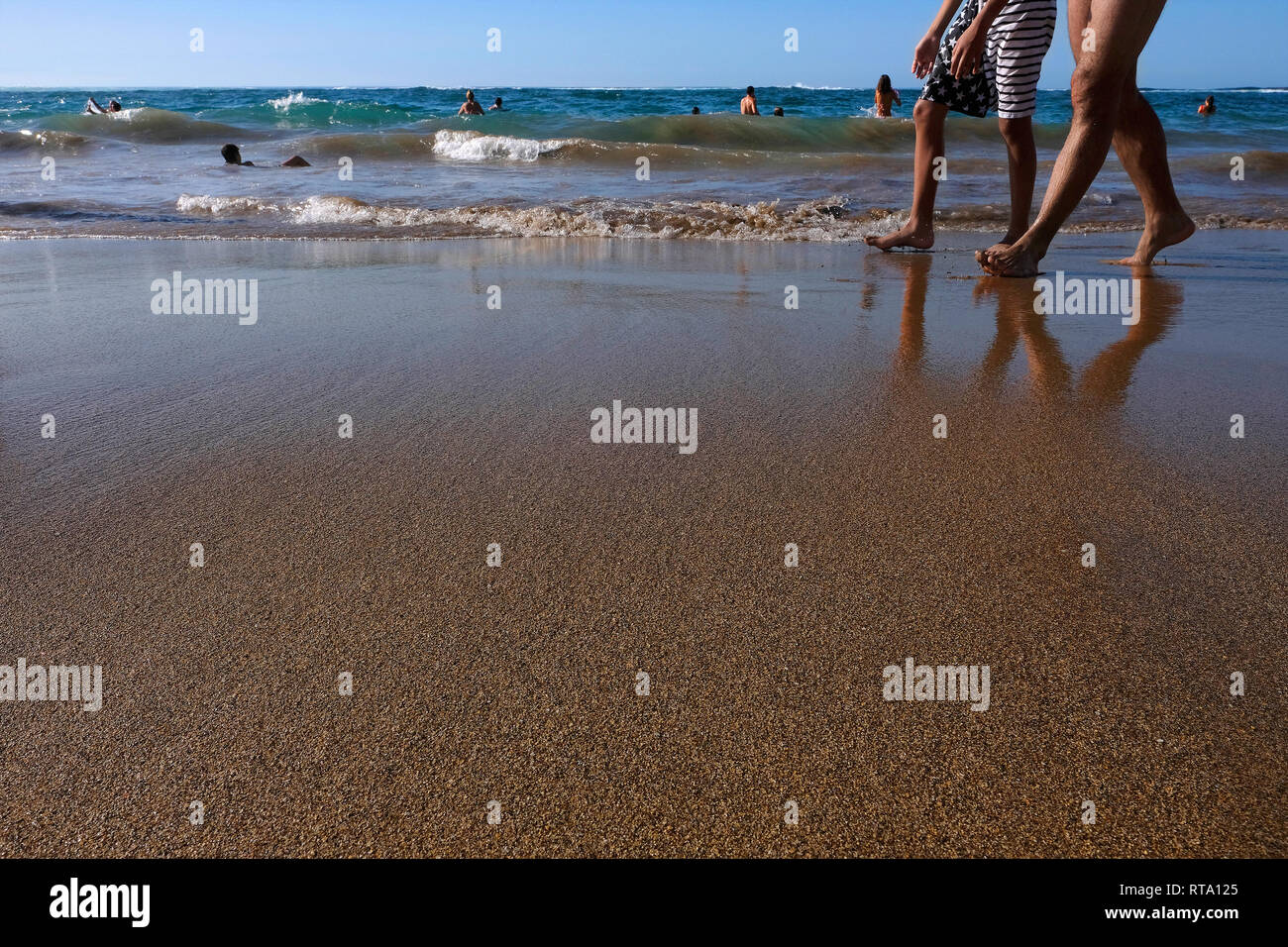 Gambe di due giovani uomini a piedi lungo la spiaggia Foto Stock