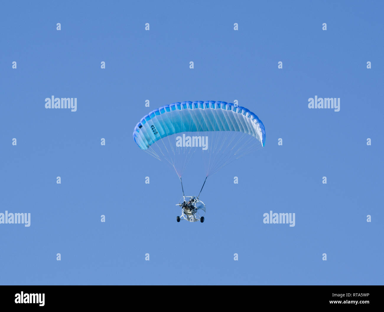 Powered parapendio volando sotto il cielo blu chiaro Foto Stock