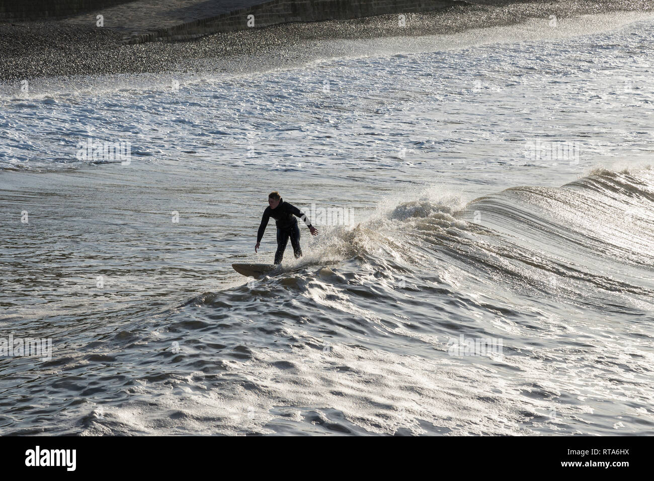 Giovane maschio surfer su un'onda a cambs, North Yorkshire, Inghilterra. Foto Stock