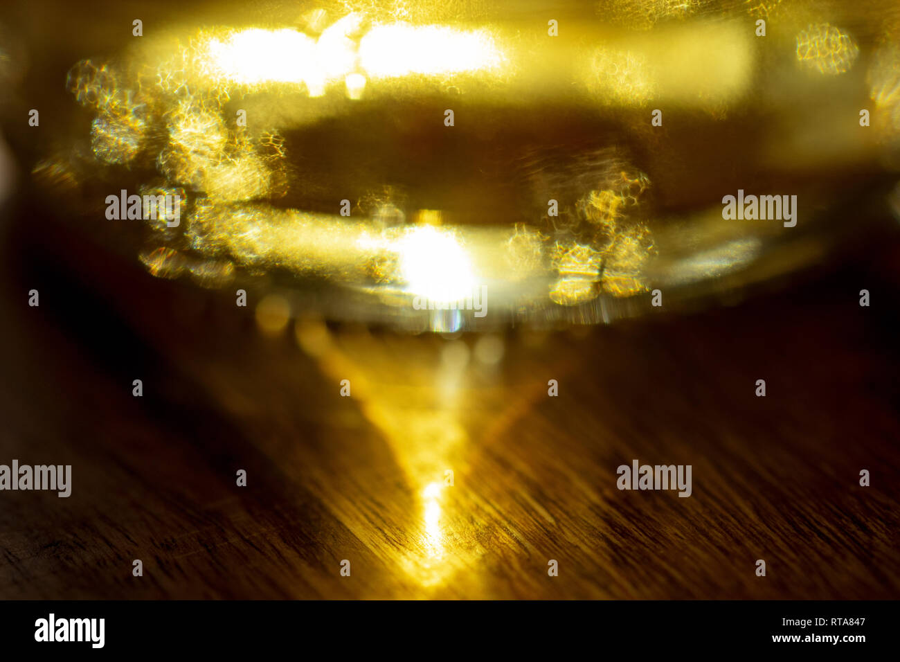 Solare pattern attraverso una bottiglia di vetro olio riflessa su una base di legno Foto Stock