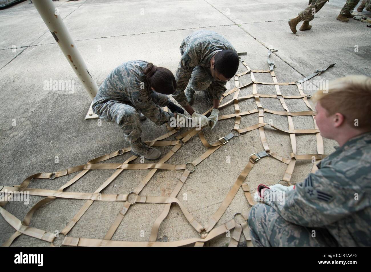 Stati Uniti Air Force Airman 1. Classe Linda Doble-Reyes, Senior Airman LaQuanne McDowell e il Senior Airman Samantha Hennancy, tutti da 59th Medical ala, districare cinghie durante la preparazione cargo pallet costruire fino a classe, Gennaio 31, 2019, a Kelly Field, Texas. La formazione militare permette ai membri la possibilità di apprendere e mettere in pratica le procedure corrette nella costruzione di pallet, eliminando gli errori a sostegno del mondo reale le contingenze. Foto Stock