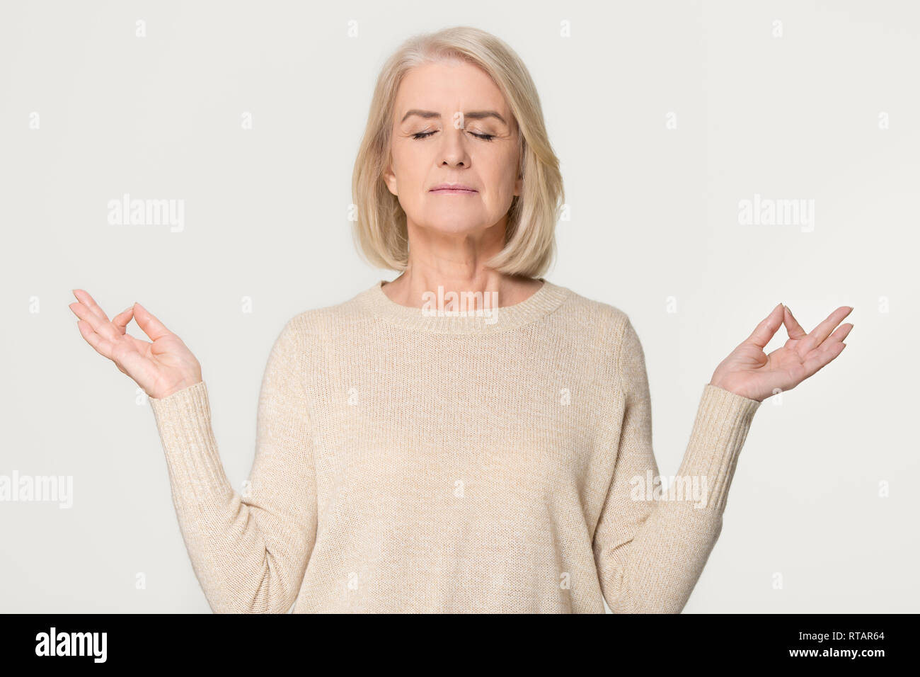 Calma sana vecchia donna meditando isolato su grigio di sfondo per studio Foto Stock