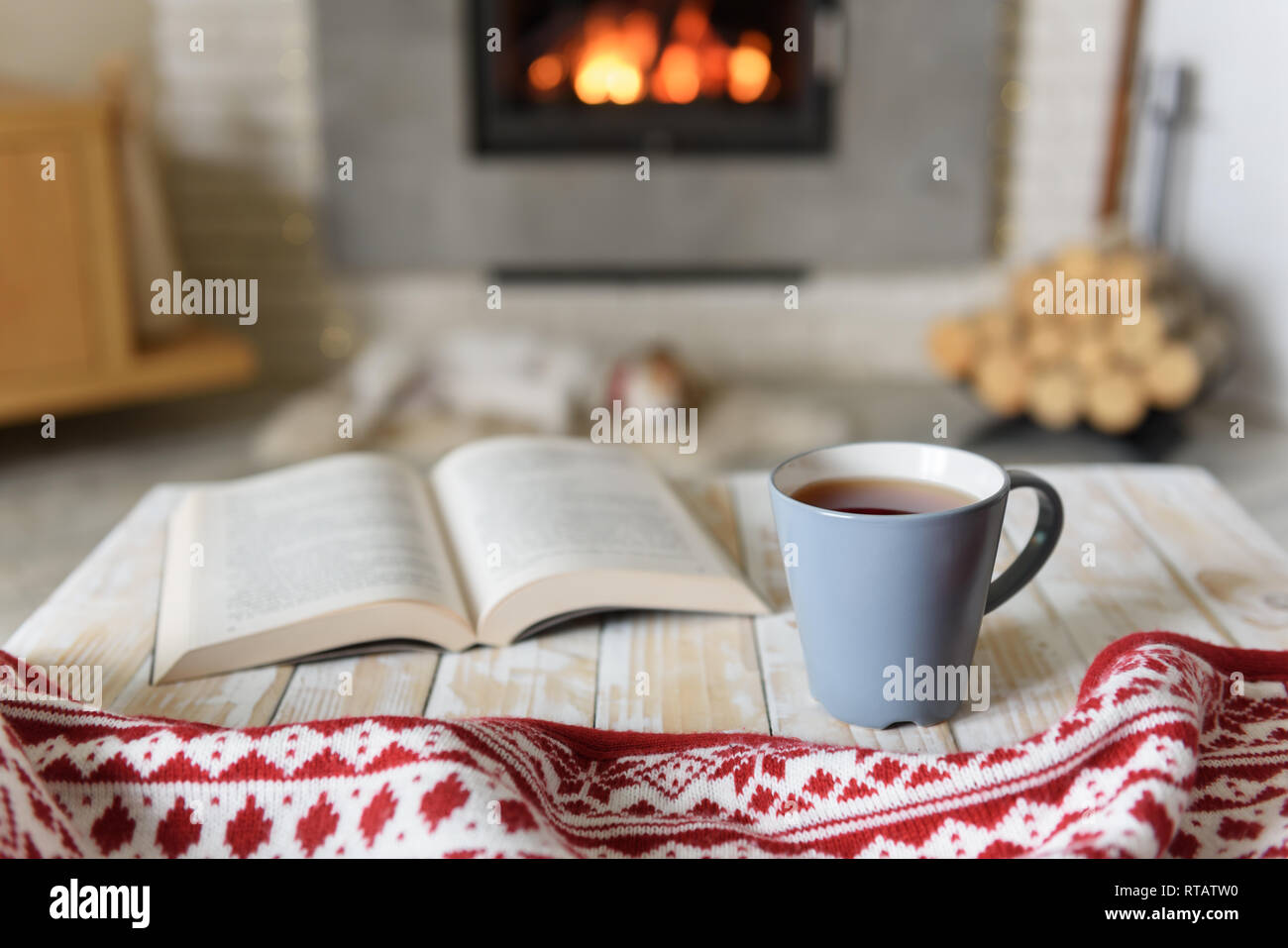 Prenota e la tazza di tè vicino al caminetto. Concetto di Hygge Foto Stock