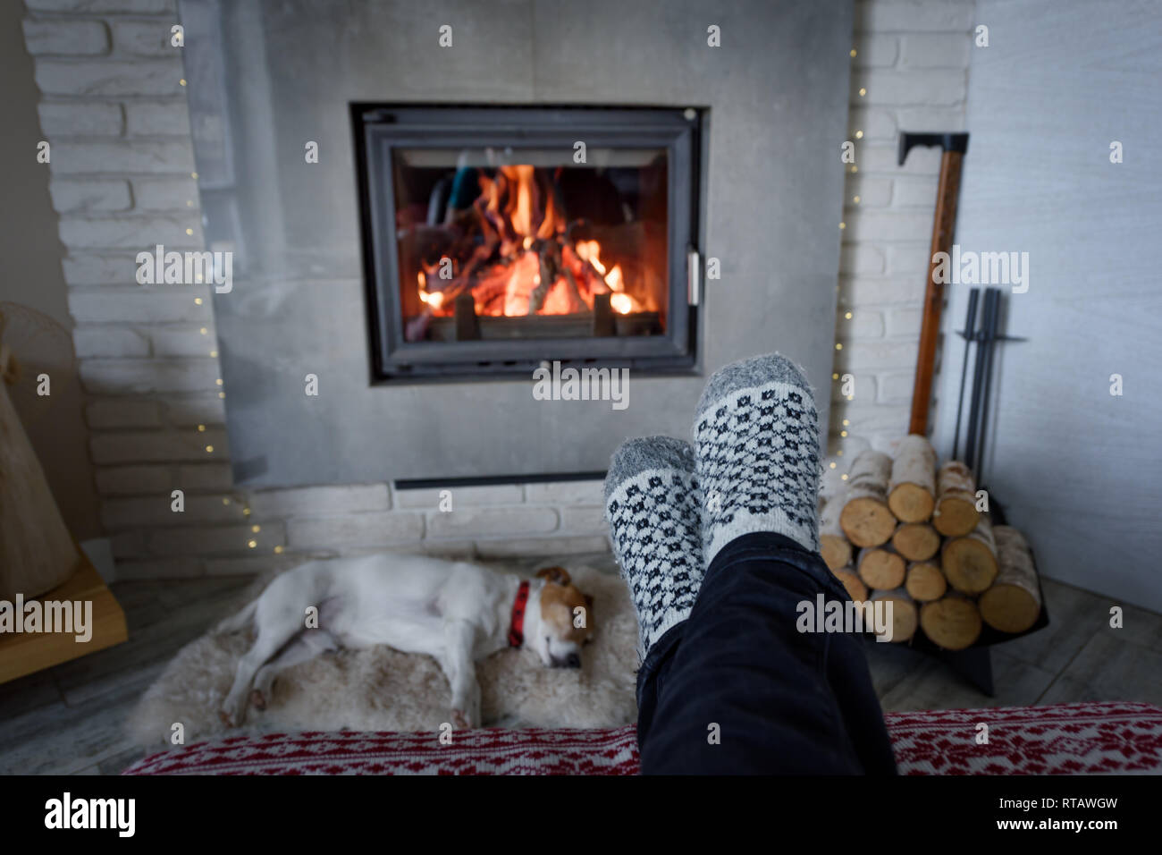 La masterizzazione di camino e un uomo in piedi in calze di lana sul primo piano. Concetto di Hygge Foto Stock
