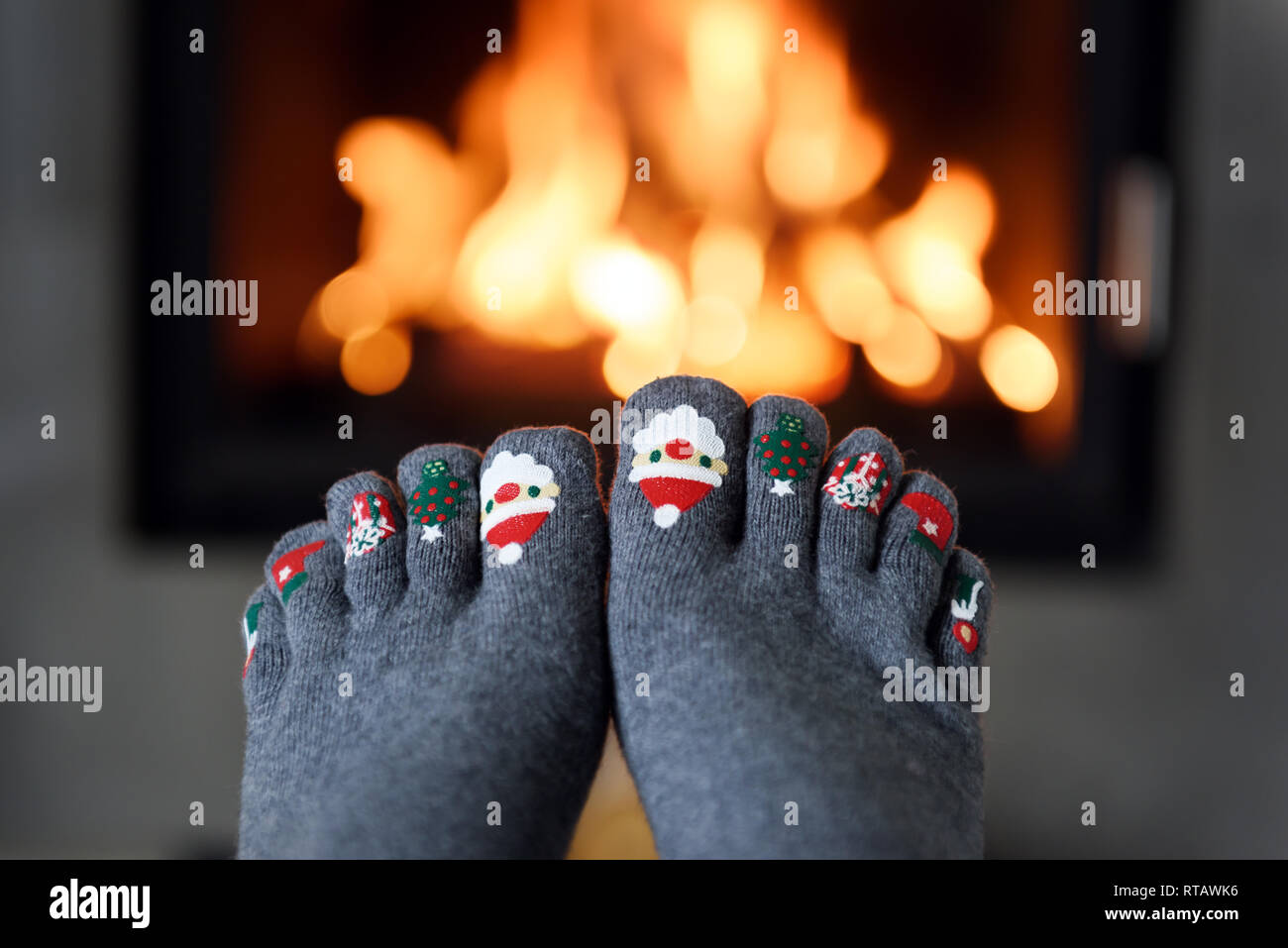 La masterizzazione di camino e una ragazza in piedi in divertenti calzini di lana sul primo piano. Concetto di Hygge Foto Stock