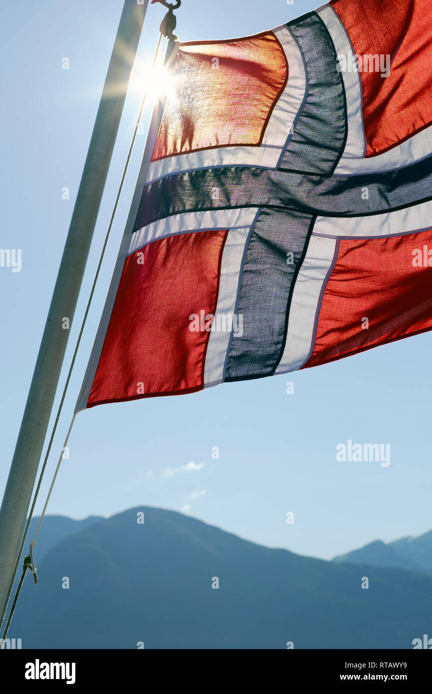 Una bandiera norvegese battenti nel sole e cielo blu Foto Stock