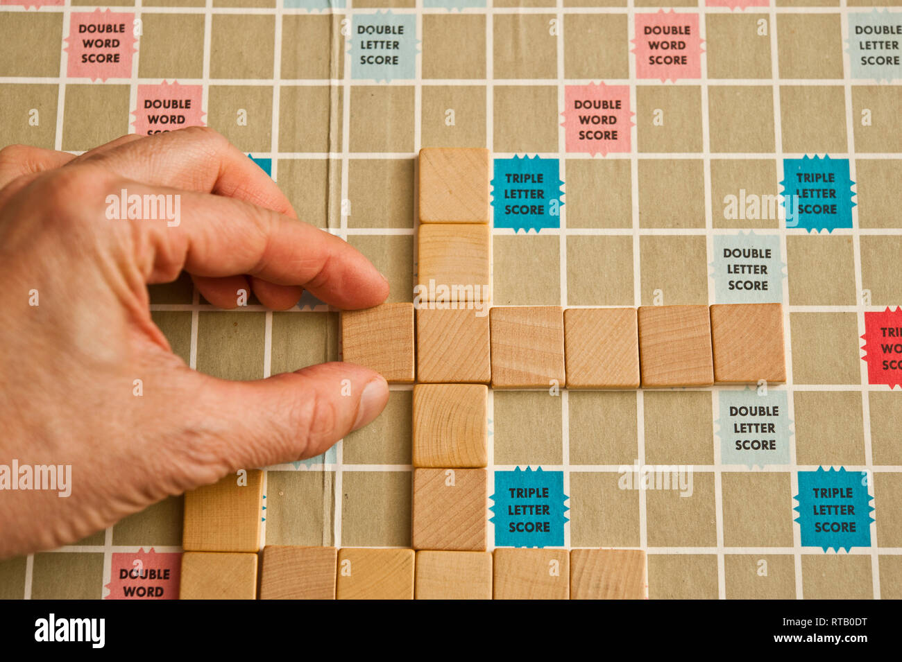 Mano e vuoto piastrelle scrabble con scheda Foto Stock