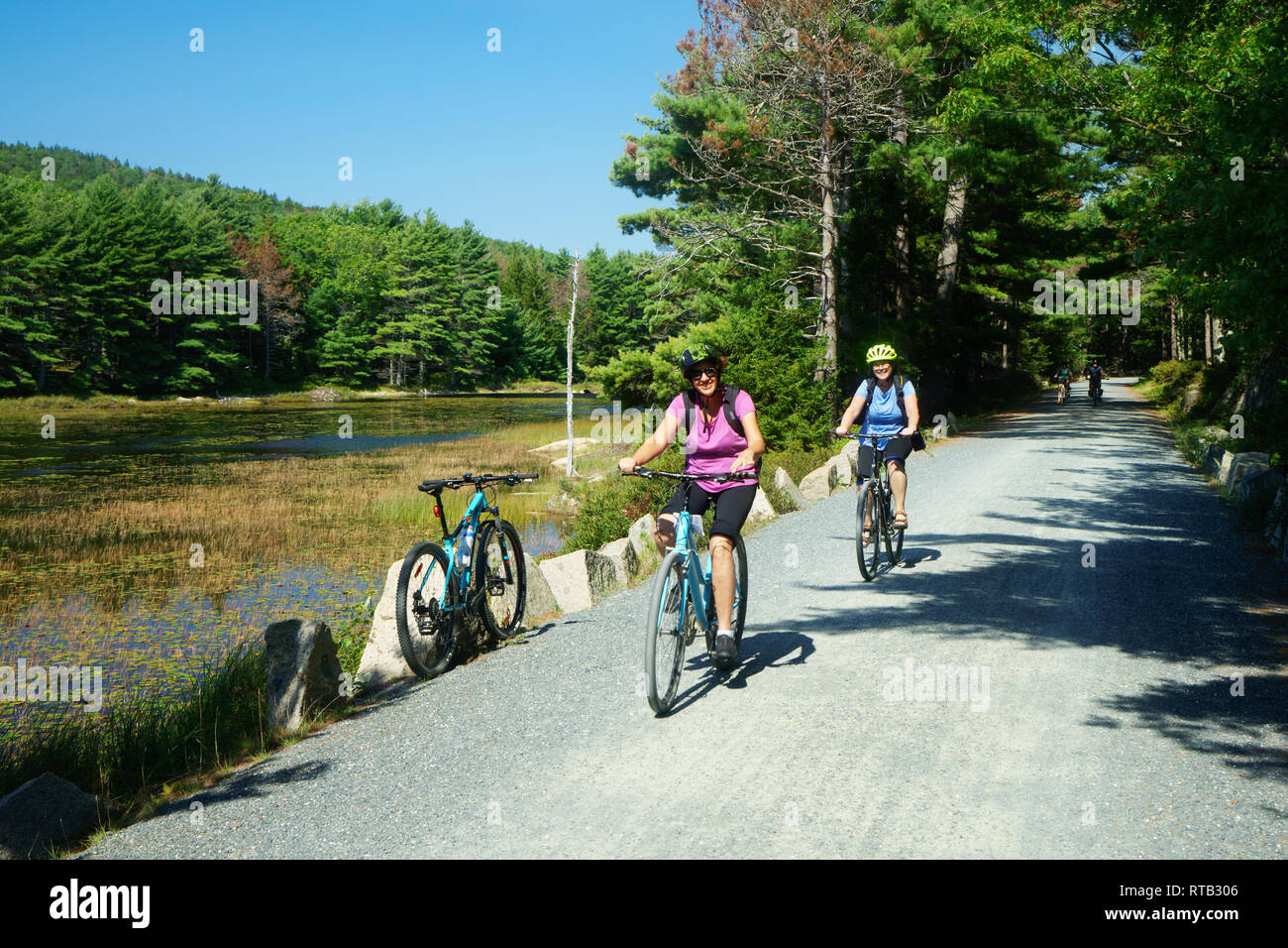 Due donne equitazione le loro biciclette sul Lago Eagle carrello loop road, Parco Nazionale di Acadia, Maine, Stati Uniti d'America. Foto Stock