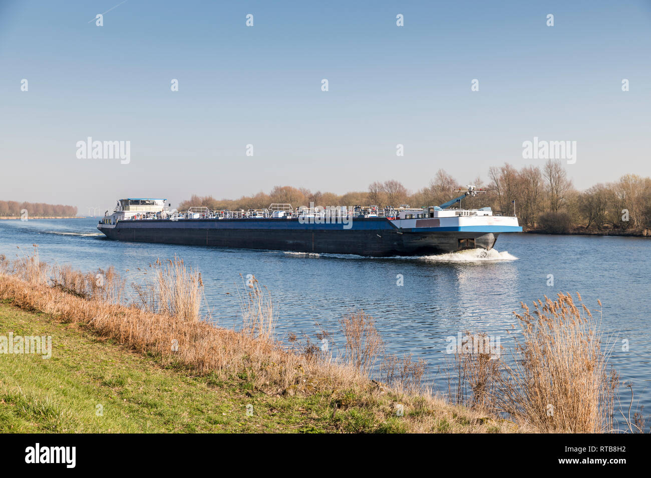 Nave da carico il trasporto in Olanda sulla Schelde rijn canal nella zona dello Zeeland con mulini a vento come sfondo Foto Stock