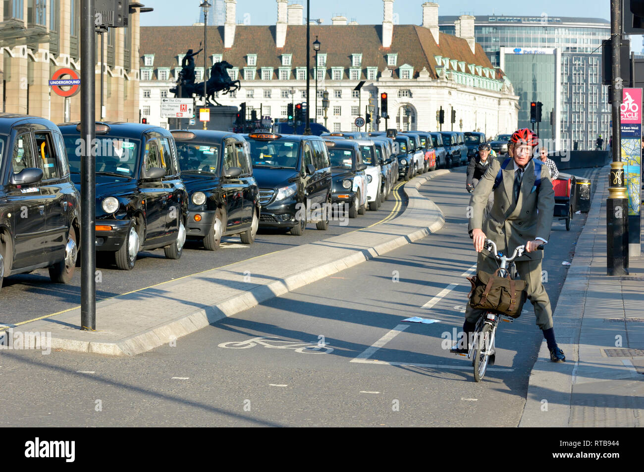 Londra, Inghilterra, Regno Unito. Protesta dei taxi sul Westminster Bridge (contro il sindaco di prevede di vietare i taxi dalla corsia di circolazione degli autobus) ciclista in pista ciclabile Foto Stock