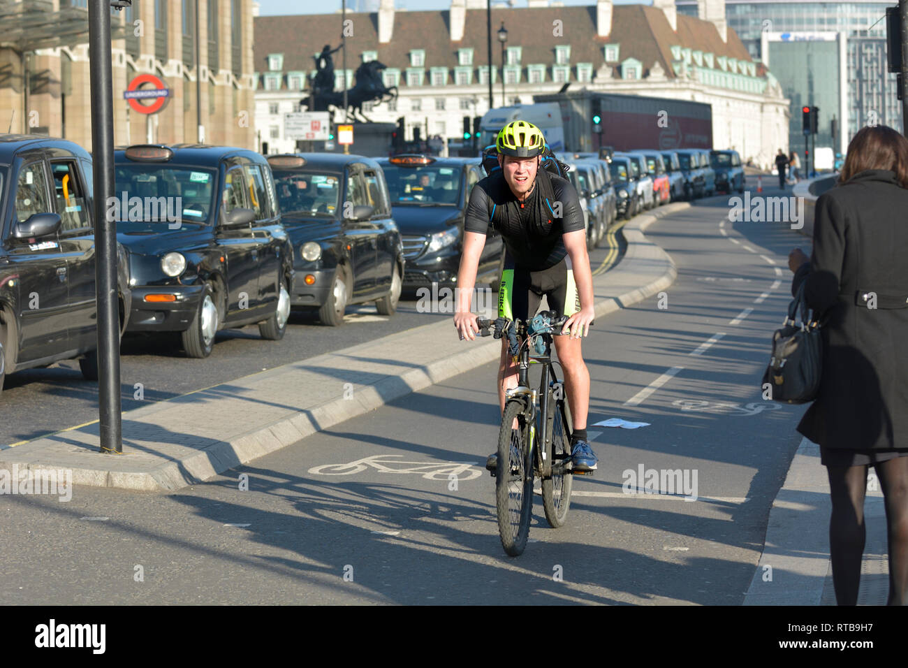 Londra, Inghilterra, Regno Unito. Protesta dei taxi sul Westminster Bridge (contro il sindaco di prevede di vietare i taxi dalla corsia di circolazione degli autobus) ciclista in pista ciclabile Foto Stock