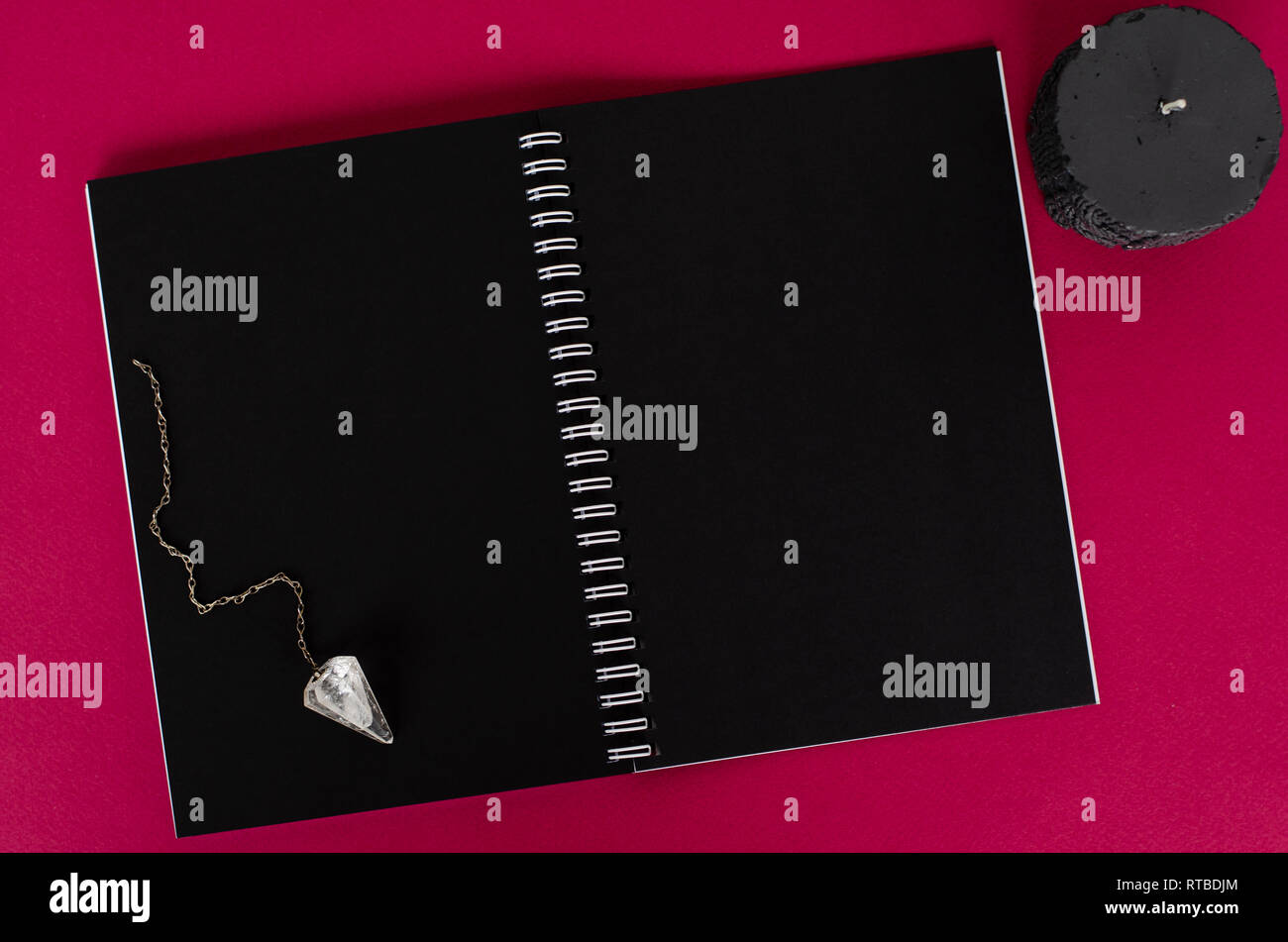Magic pendolo, nero candela e aperto il notebook con fogli nero su sfondo scuro. Vista dall'alto. Lay piatto Foto Stock