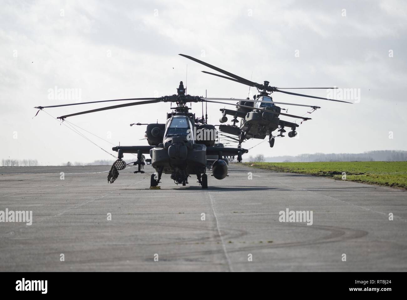 Un U.S. Esercito AH-64 elicottero Apache dal primo combattimento Brigata Aerea, 1a divisione di fanteria, rompe la linea come foglie Wingene Air Base, Belgio, Feb 07, 2019. Wingene Air Base è servita come un intermedio area di sosta prima della 1a combattere la Brigata Aerea distribuisce in Germania, Polonia, Lettonia e Romania per nove mesi al treno con i partner della NATO a sostegno della Atlantic risolvere. Foto Stock