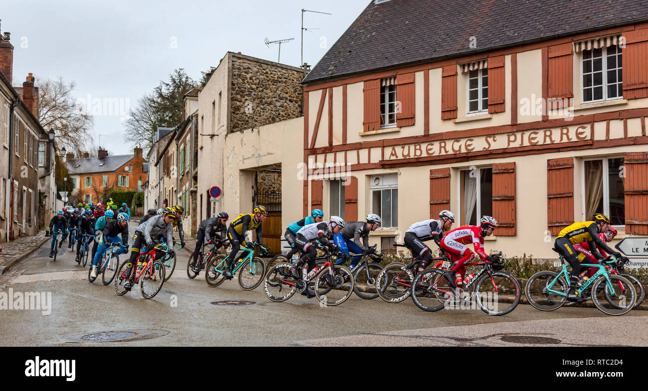 Dampierre-en-Yvelines, Francia - 4 Marzo 2018: Il Peloton passa davanti ad edifici tradizionali su una piccola strada in un villaggio francese durante la pari Foto Stock