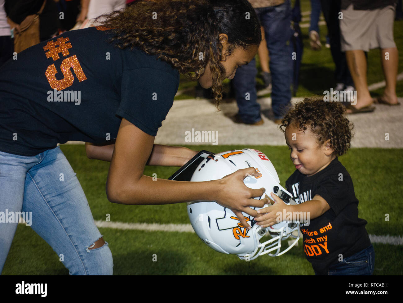 Refugio studente di scuola superiore Alexa Valenzuela mani running back Jacobe Avery's casco a suo figlio, Kameron Avery, Sett. 29, 2017, in Seguin, Texas. Foto Stock