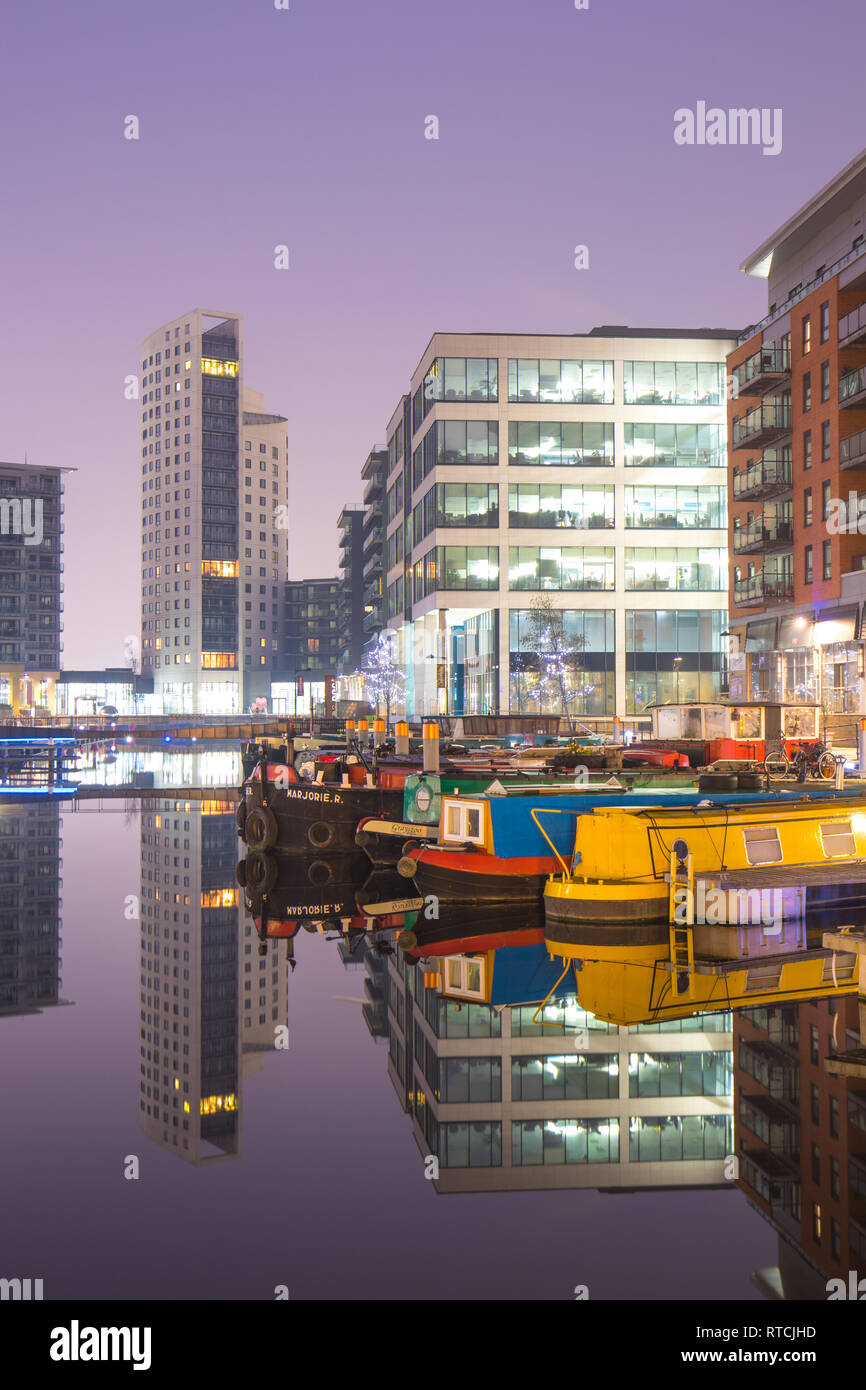 Le riflessioni di ormeggiati narrowboats e appartamenti a Leeds Dock Foto Stock