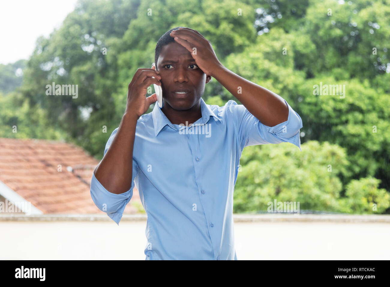 Scioccato americano africano uomo d affari al telefono all'aperto in Africa Foto Stock