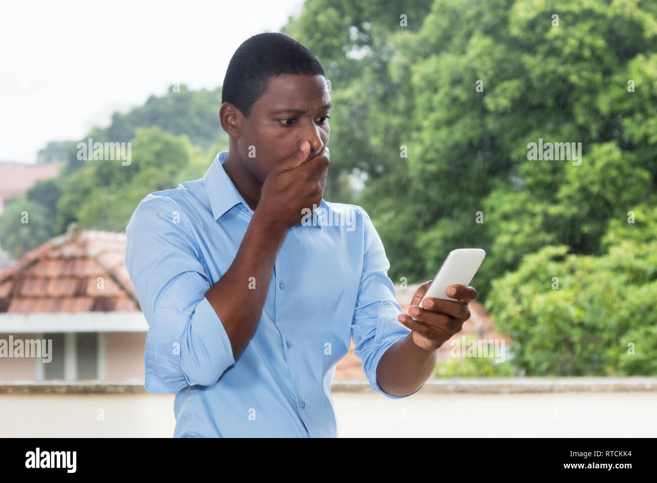 African American businessman la ricezione di un messaggio di testo con le cattive notizie all'esterno in Africa Foto Stock