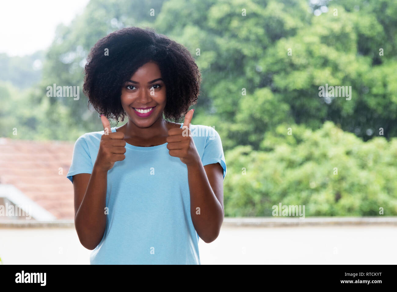Carino americano africano donna che mostra entrambi i pollici fino all'aperto Foto Stock