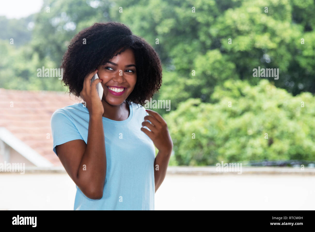 Bella americano africano Donna che parla al telefono cellulare all'aperto Foto Stock