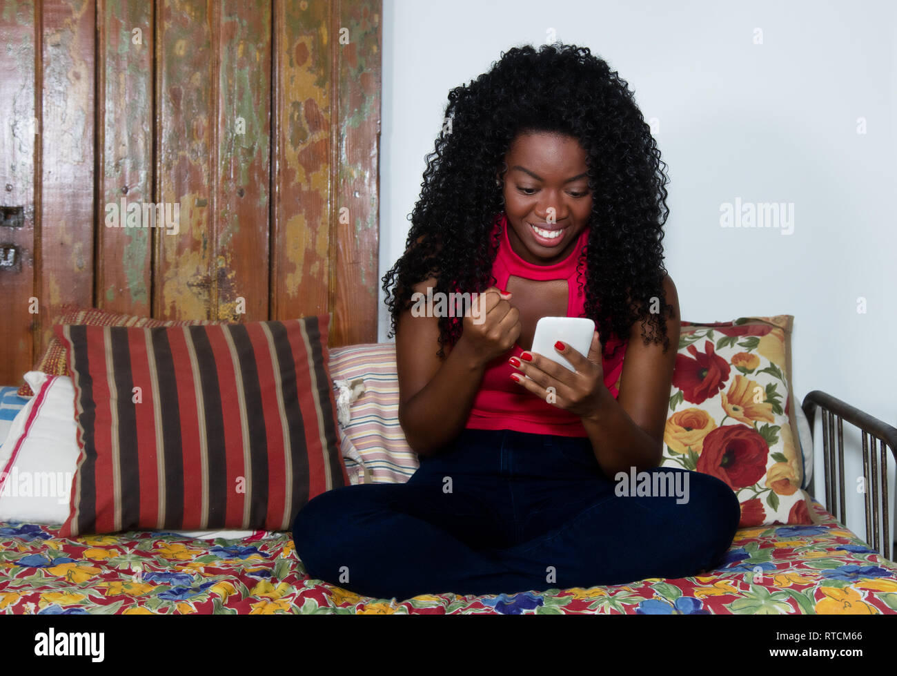 Il tifo americano africano donna con telefono sul lettino a casa Foto Stock
