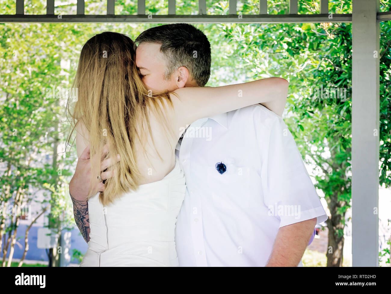 La sposa e lo sposo abbraccio come esse sono pronunciate l uomo e la moglie presso il Marshall Park in Ocean Springs, Mississippi. Foto Stock