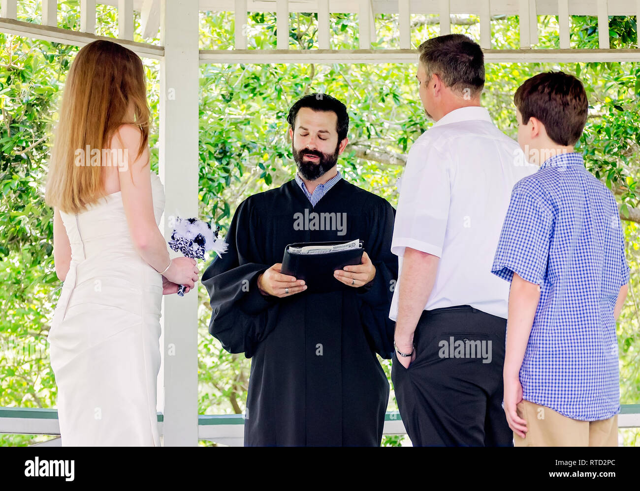 Un predicatore parla di una coppia appena sposata e il loro figlio dopo un matrimonio nel Parco di Marshall in Ocean Springs, Mississippi. Foto Stock