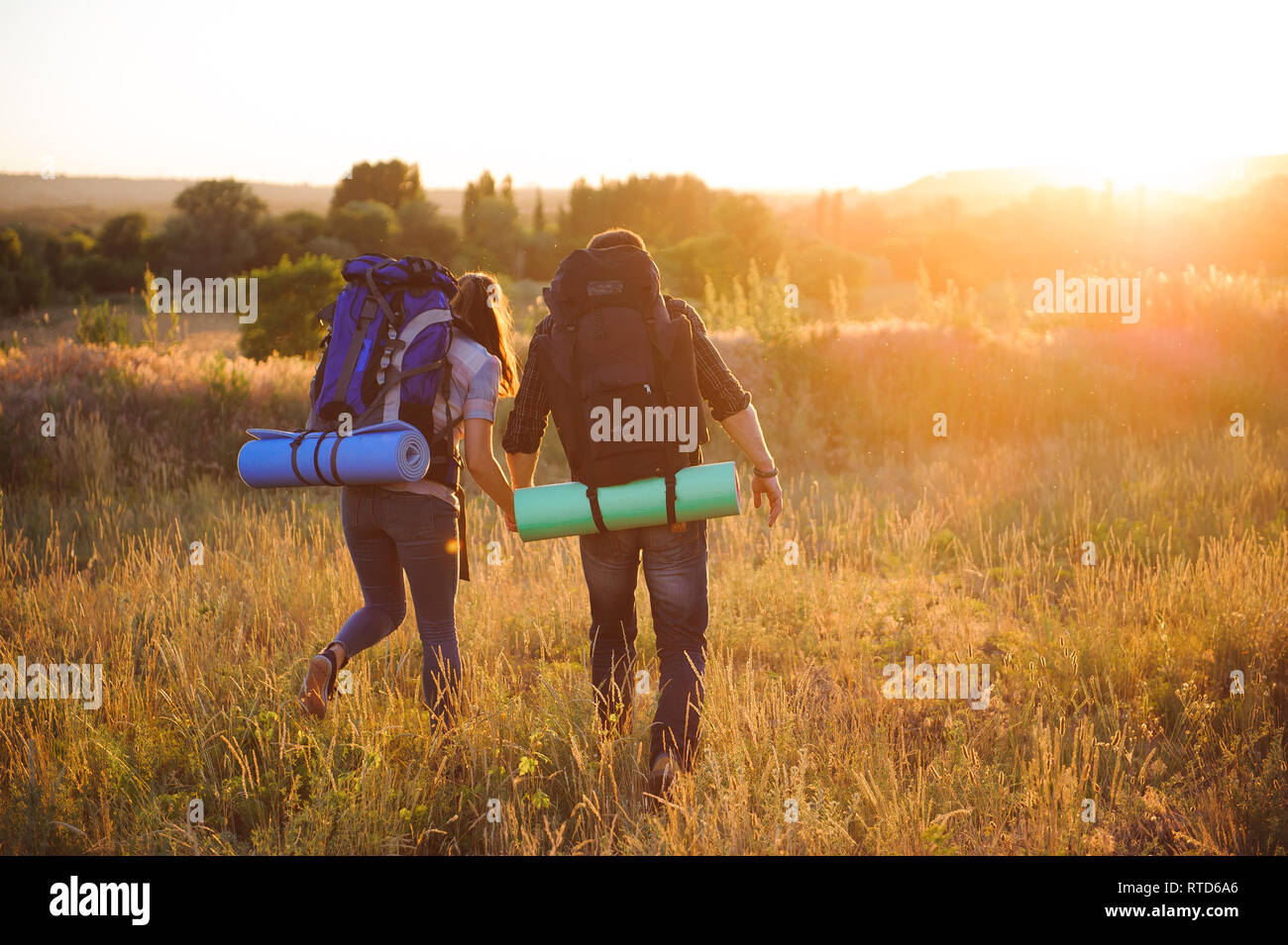 I viaggiatori con zaino camminando nel tramonto all'esterno. Foto Stock