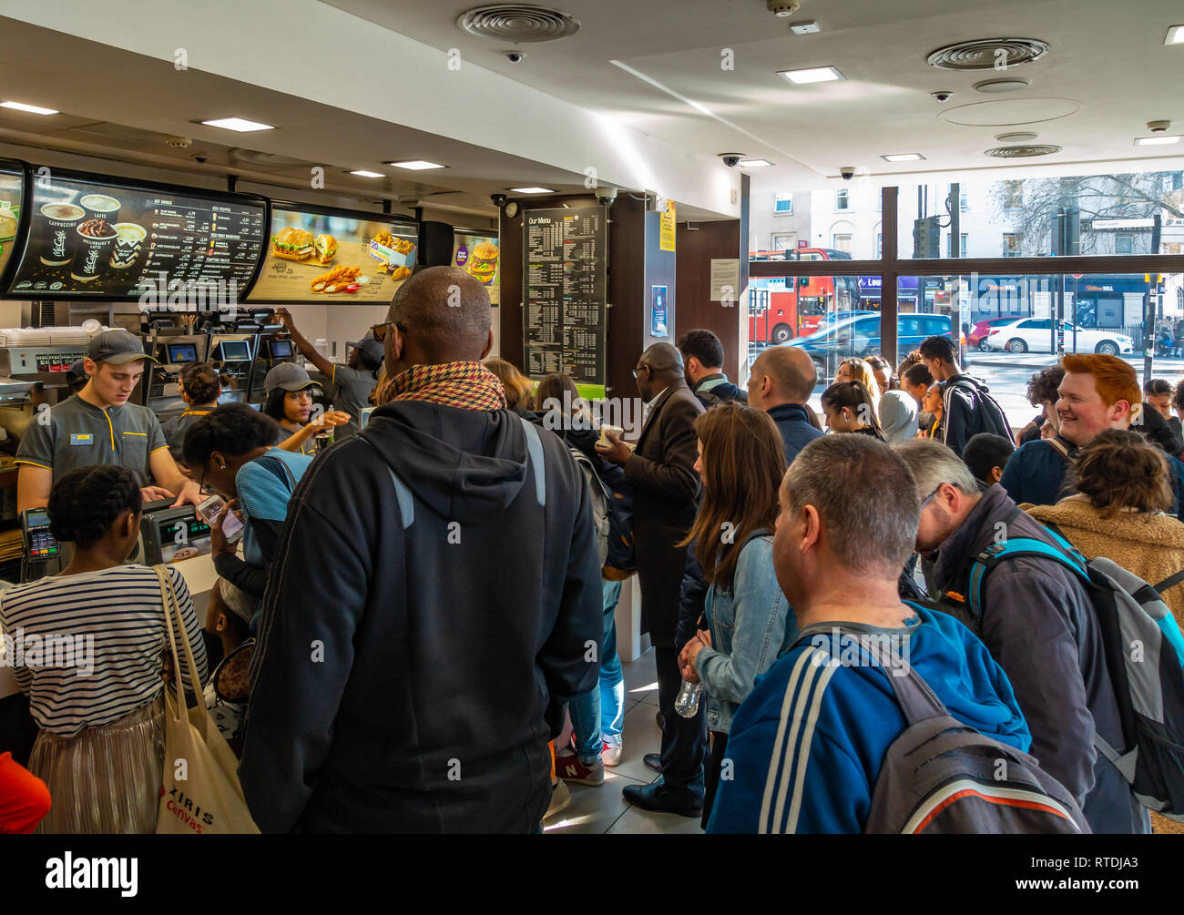 Coda di grandi dimensioni di persone in attesa di essere serviti a McDonalds, Kings Cross a Londra, Inghilterra Foto Stock