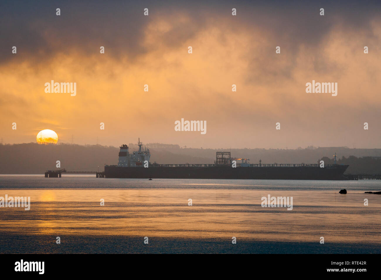 Whitegate, Cork, Irlanda. Ist marzo, 2019. Sunrise solleva la foschia e la nebbia per rivelare la sovrastruttura del 250 metri di olio grezzo tanker Searanger essendo scaricata al Whitegate raffineria di petrolio in Co. Cork, Irlanda. Credito: David Creedon/Alamy Live News Foto Stock