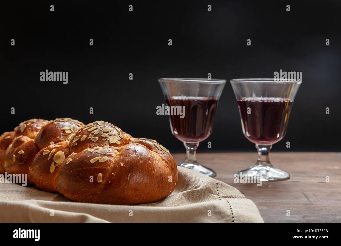 Concetto di Shabbat, challah pane con due bicchieri di vino rosso sul tavolo di legno Foto Stock