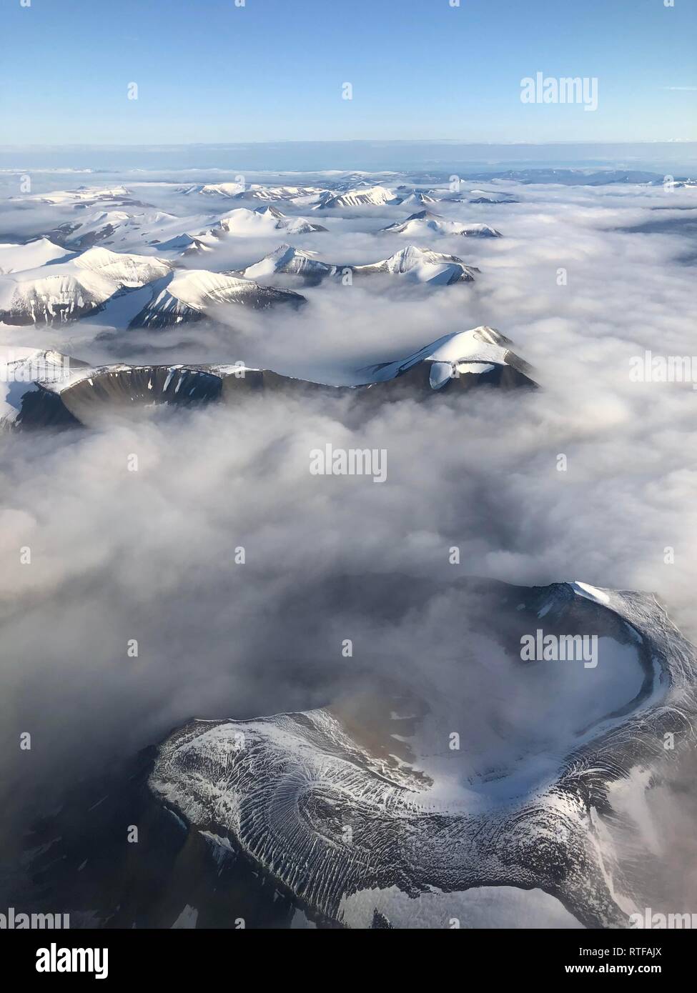 Vista aerea, picco di montagna con la neve sopra la copertura nuvolosa, Spitsbergen, Svalbard, Norvegia Foto Stock