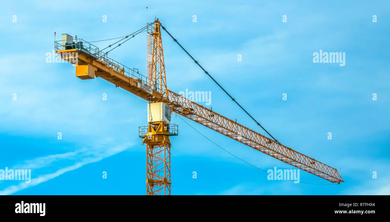 Enorme costruzione di gru a torre e nuvoloso cielo blu. Vista ravvicinata di un enorme giallo gru a torre utilizzate per la movimentazione di materiali pesanti su una costruzione s Foto Stock