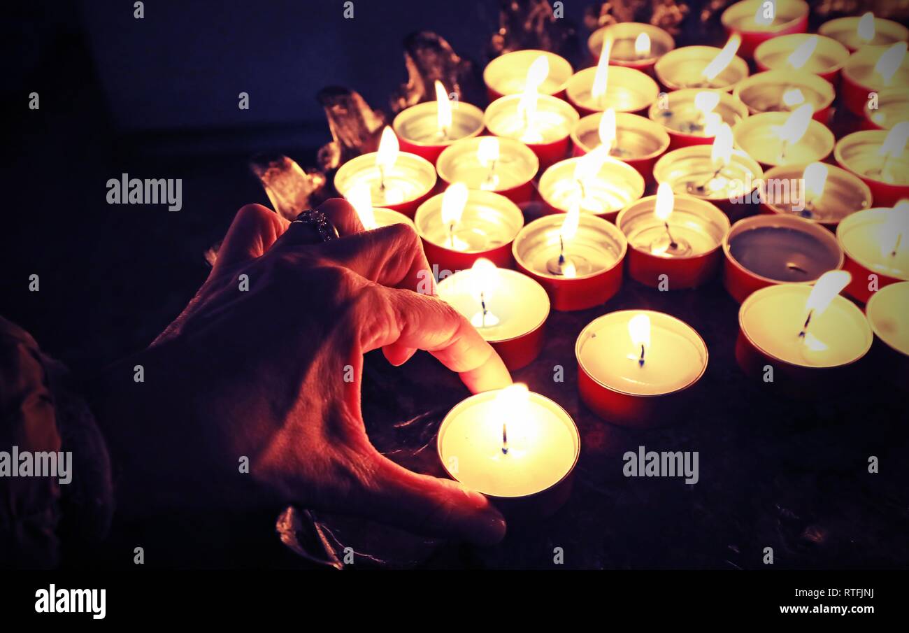 Mano di donna e candele nel luogo di culto Foto Stock