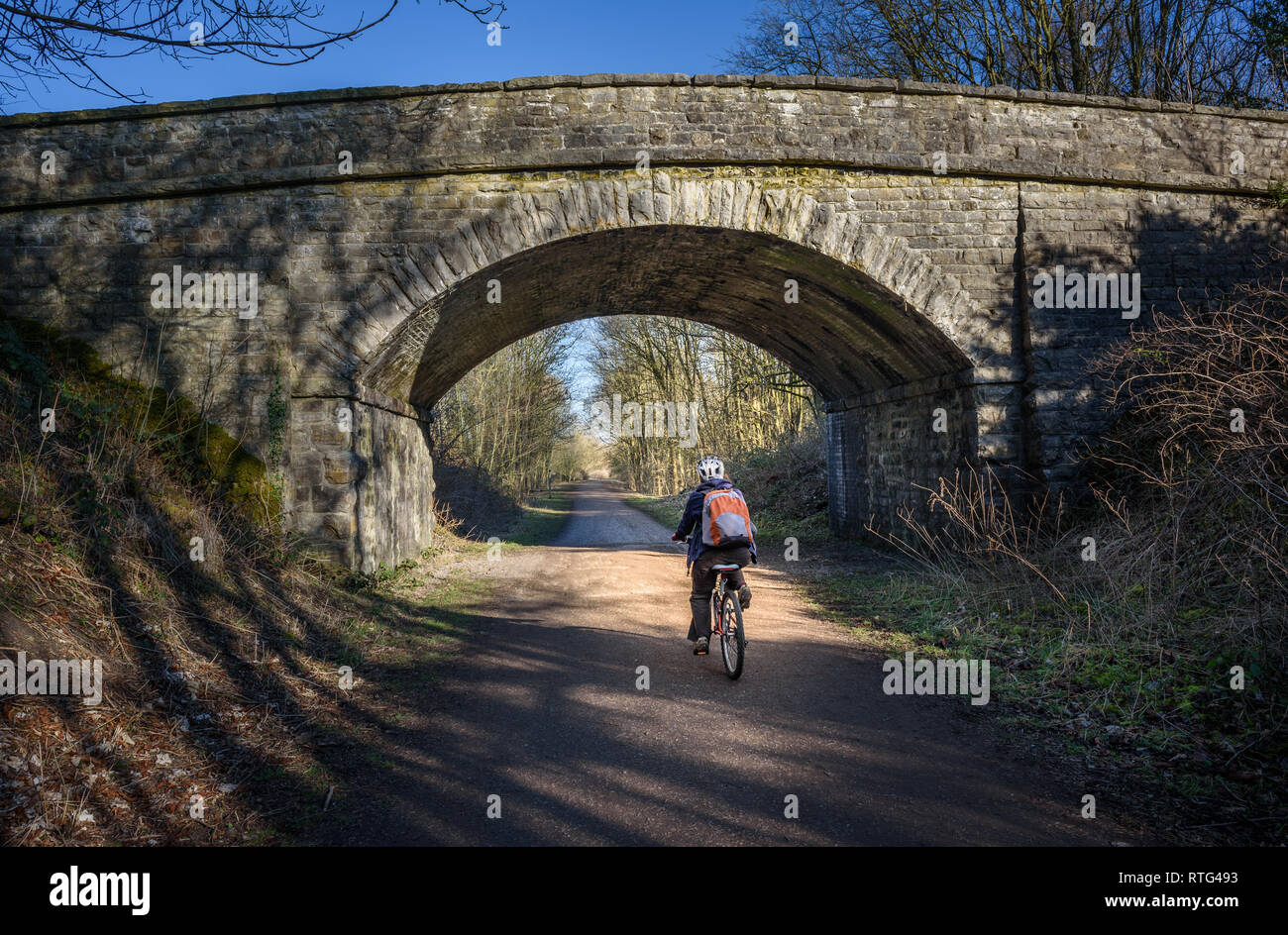 Un ciclista passando sotto uno dei viadotti ferroviari su teh Monsal Trail, Derbyshire, Peak District, UK. Foto Stock