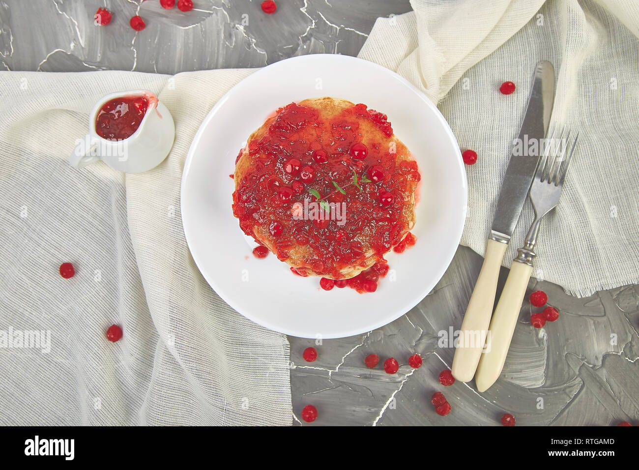 American pancake con la marmellata - berry, pallon di maggio, mirtillo rosso su sfondo grigio. Pancake fatti in casa con salsa di frutti di bosco e le foglie di menta. Sana colazione con prodotti freschi h Foto Stock