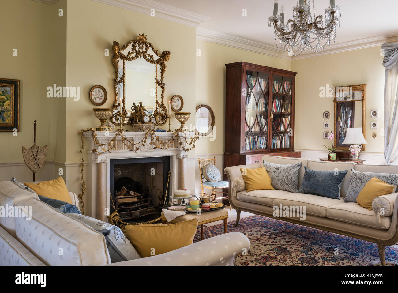 Tappeto orientale con stile regency divani e foglia oro garland sul camino inglese Foto Stock