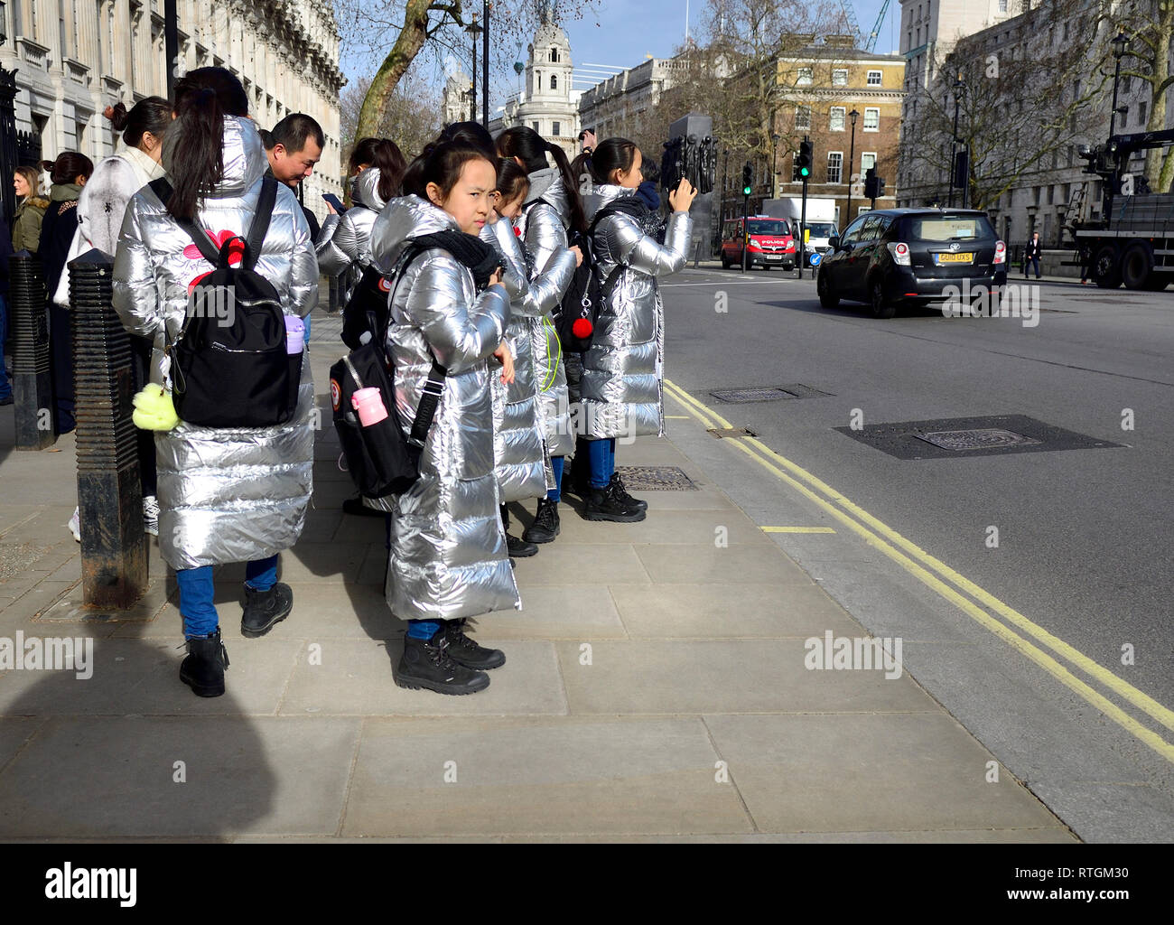 Londra, Inghilterra, Regno Unito. Gruppo di visitare gli scolari giapponesi in argento identici cappotti in Whitehall, al di fuori di Downing Street Foto Stock